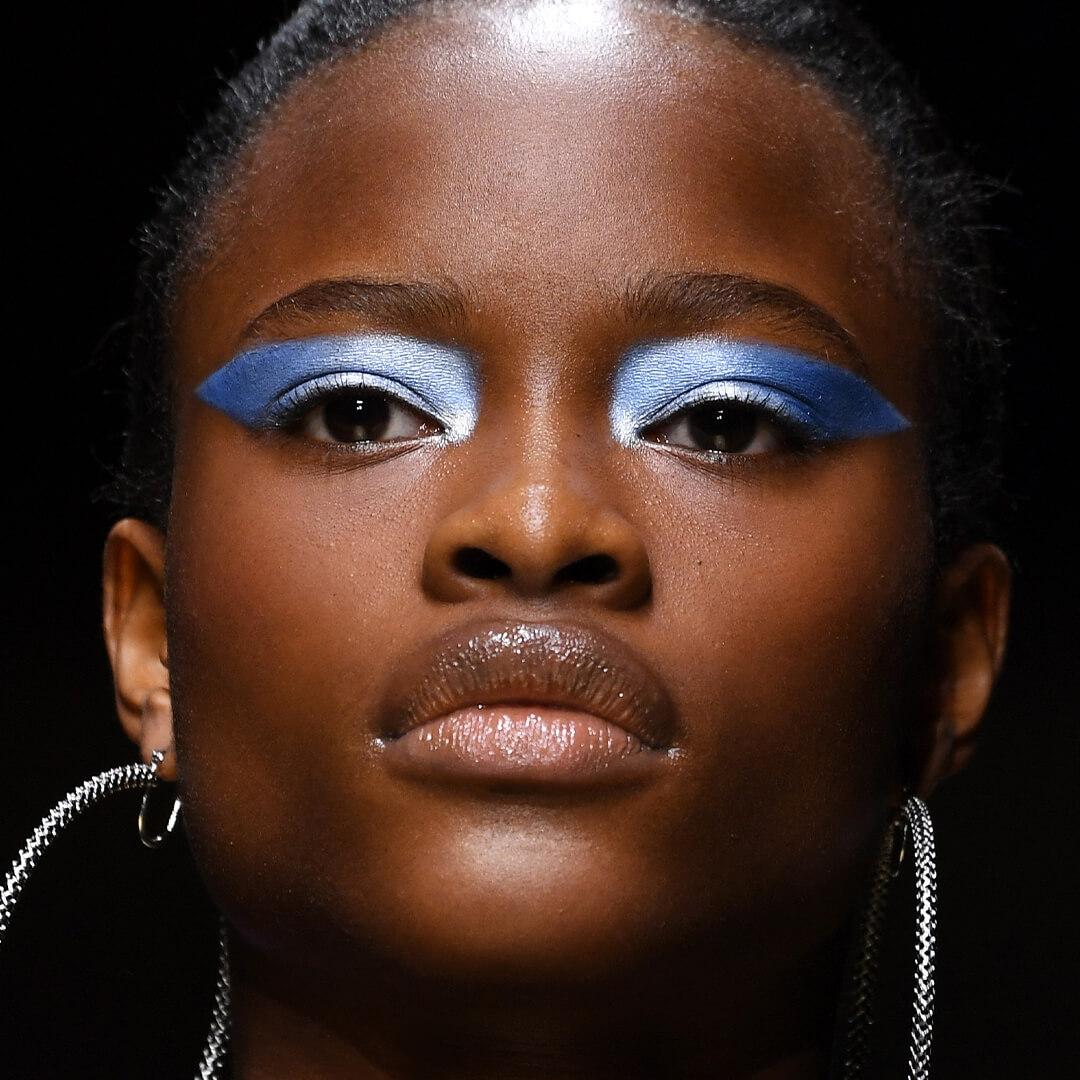 Close-up image of a black female model rocking a geometric shimmery blue eyeshadow look