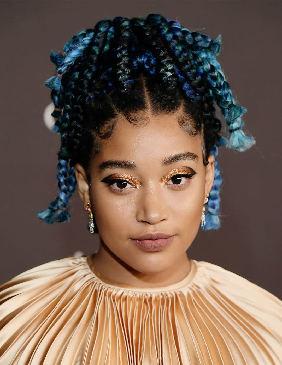 Amandla Stenberg looking glamorous in a textured cream dress and waterfall braided hairstyle