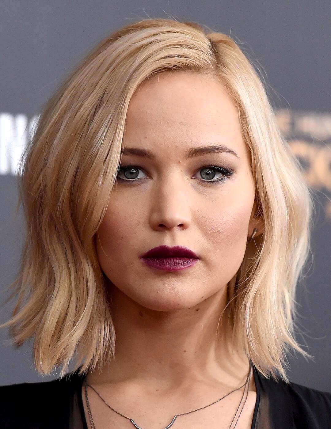 A photo of Jennifer Lawrence looking fierce in her wavy, blonde hair with purple lipstick