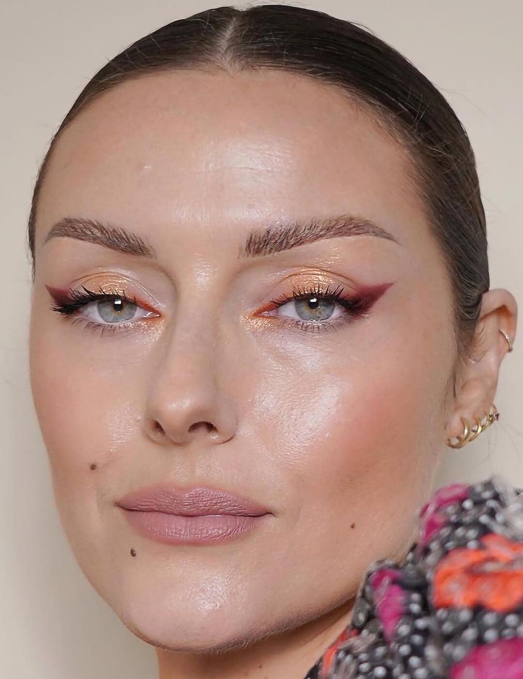 Close-up of a woman rocking a peachy glitter eye makeup look and nude lips