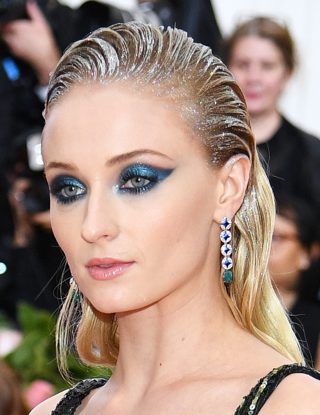 Sophie Turner looking glam in a metallic blue eyeshadow makeup look and silver hair accents on the 2019 Met Gala red carpet