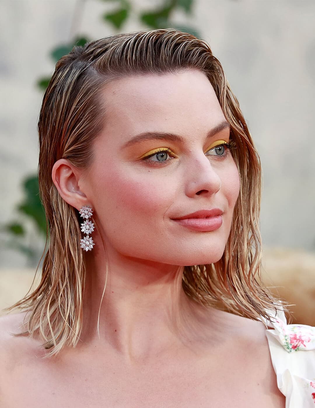 A photo of Margot Robbie with a wet look hairstyle with bright yellow eyeshadow