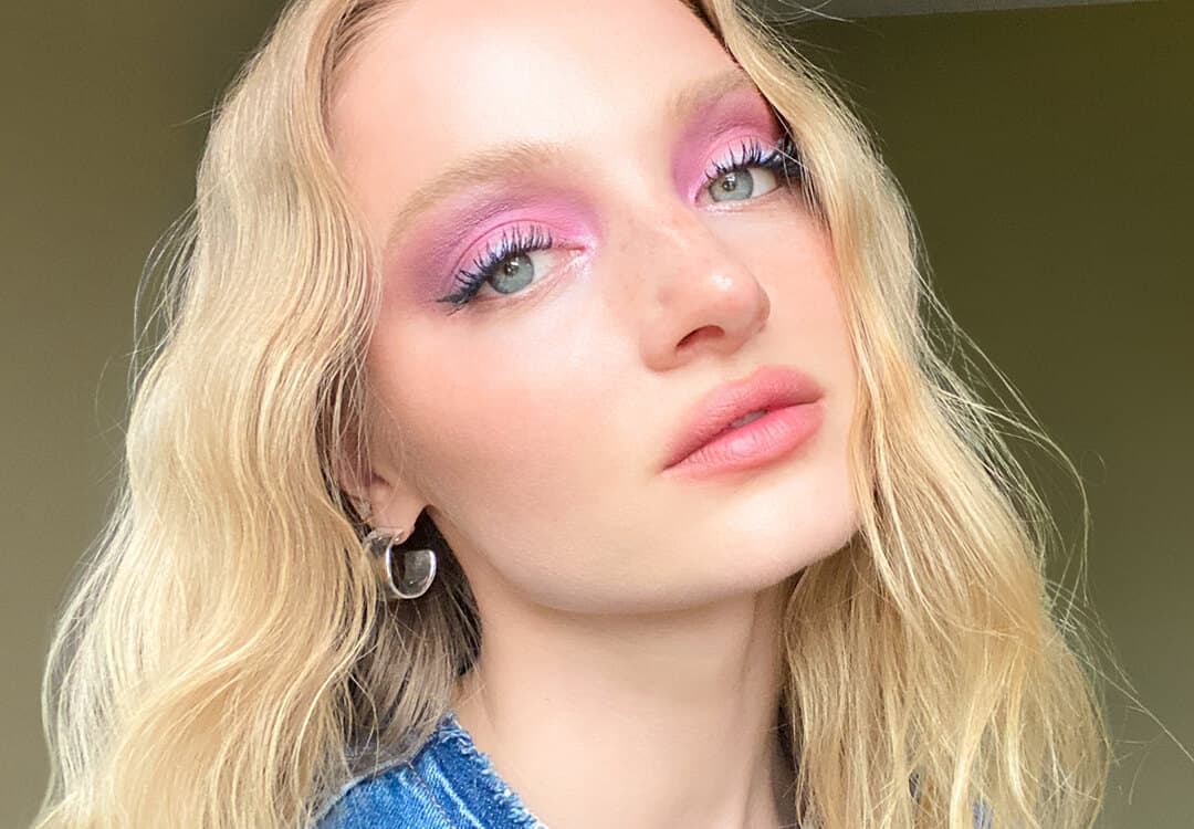 A close-up image of Ash Walker wearing a pink and shimmery purple eyeshadow look