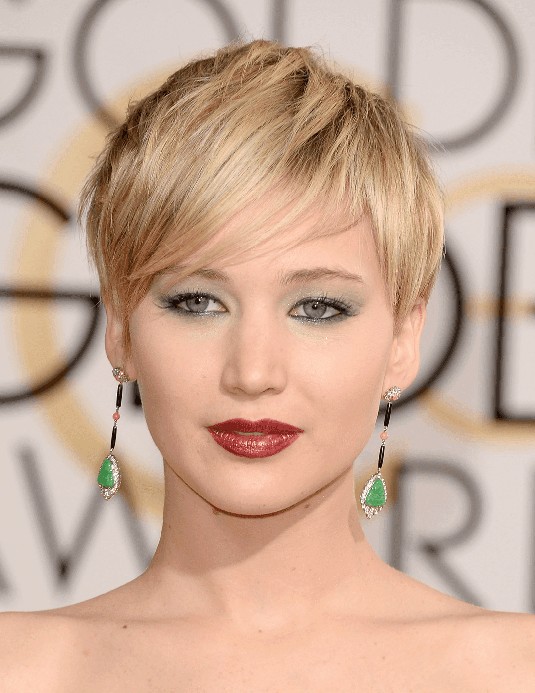 Jennifer Lawrence rocking a sultry makeup look, dangling emerald earrings, and messy pixie hairstyle