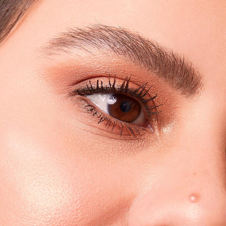 A closeup image of a model wearing shimmery, bronze eyeshadow and highlighter