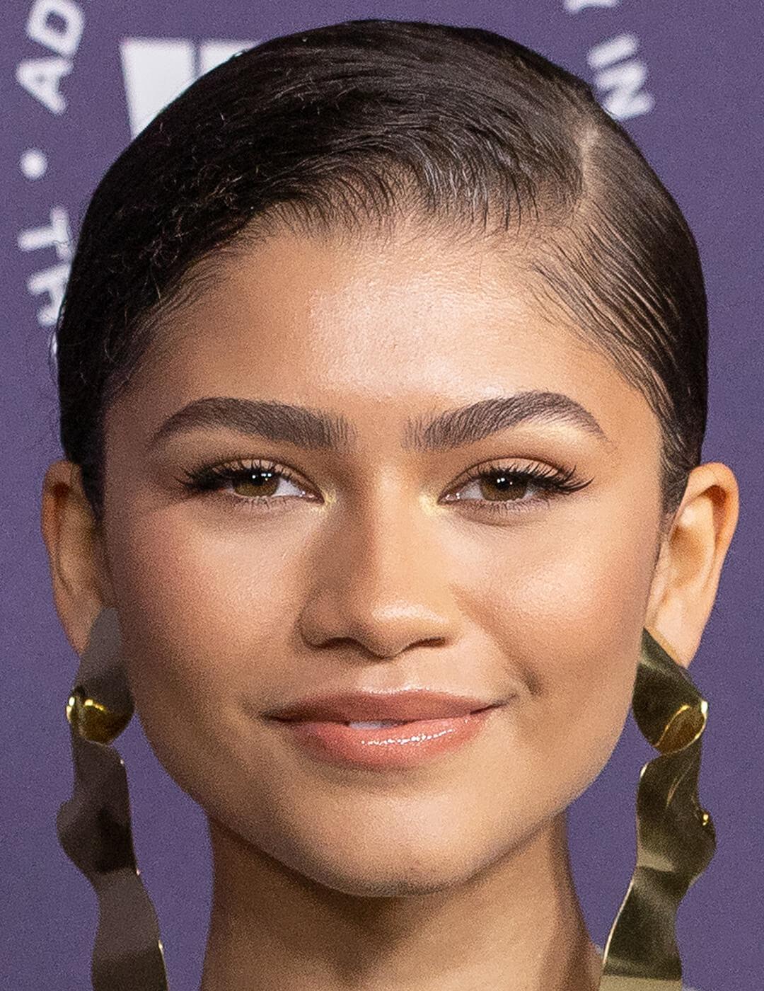 A photo of Zendaya with a neutral makeup look, wearing gold earrings