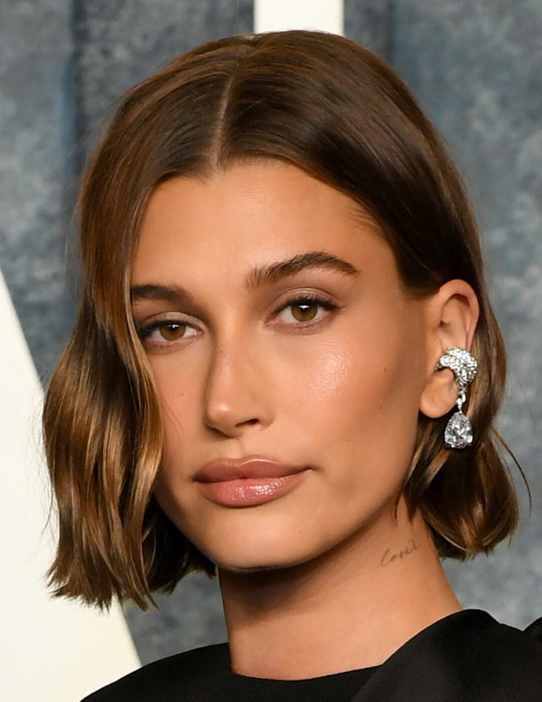 Close-up look of Hailey Bieber rocking a subtle makeup style, paired with her chic blunt mini bob hairstyle with Crystal Clip Earrings in a stylish tear-drop design