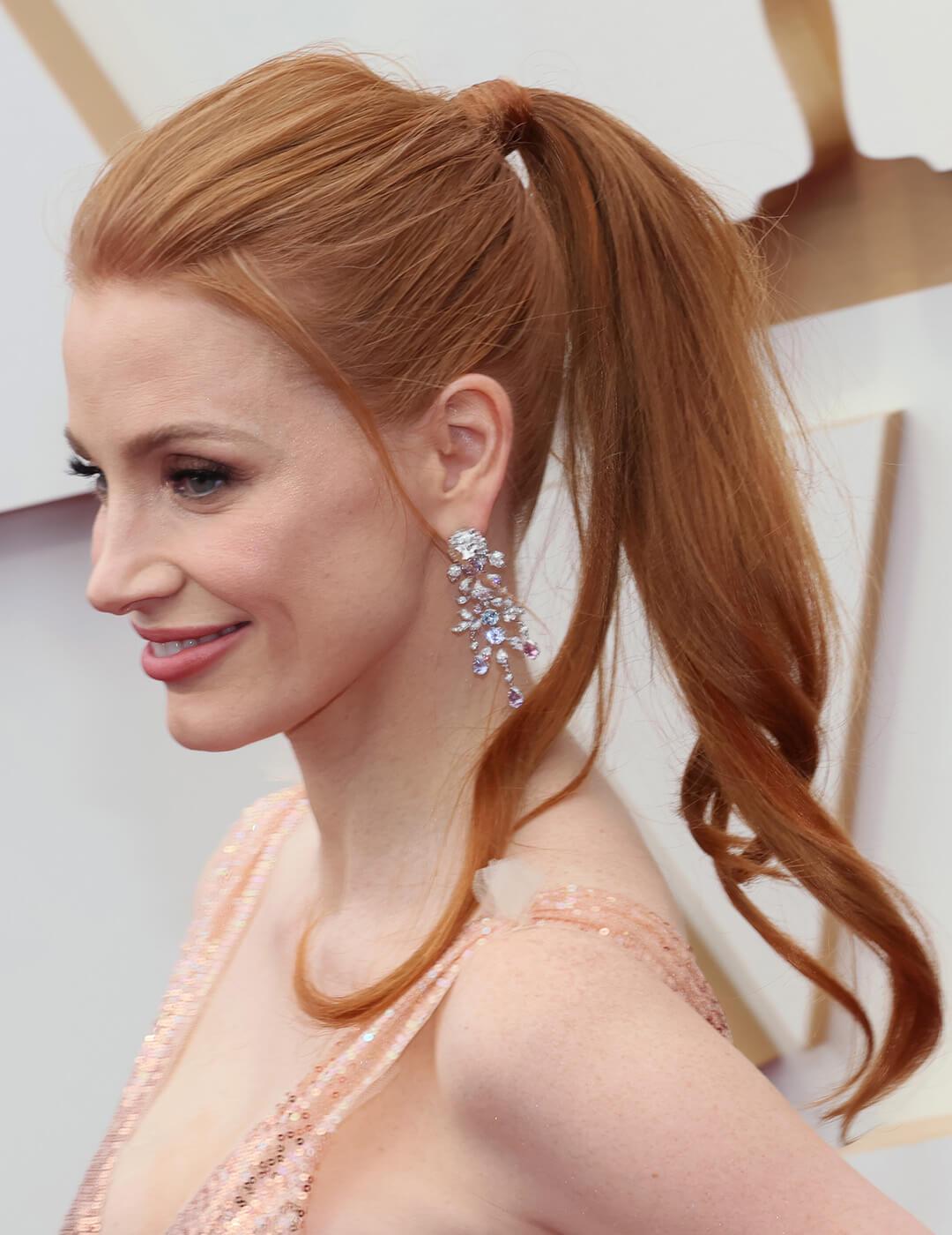 Jessica Chastain rocking a ponytail hairstyle, stone-studded dangling earrings and pink sequined dress
