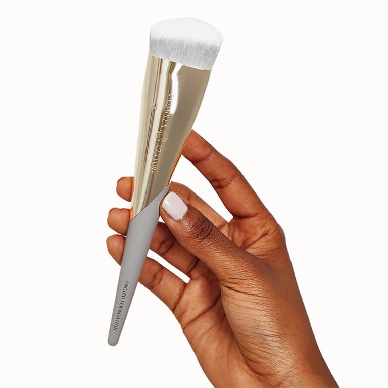 A model holding up the COMPLEX CULTURE Angled Foundation Brush.