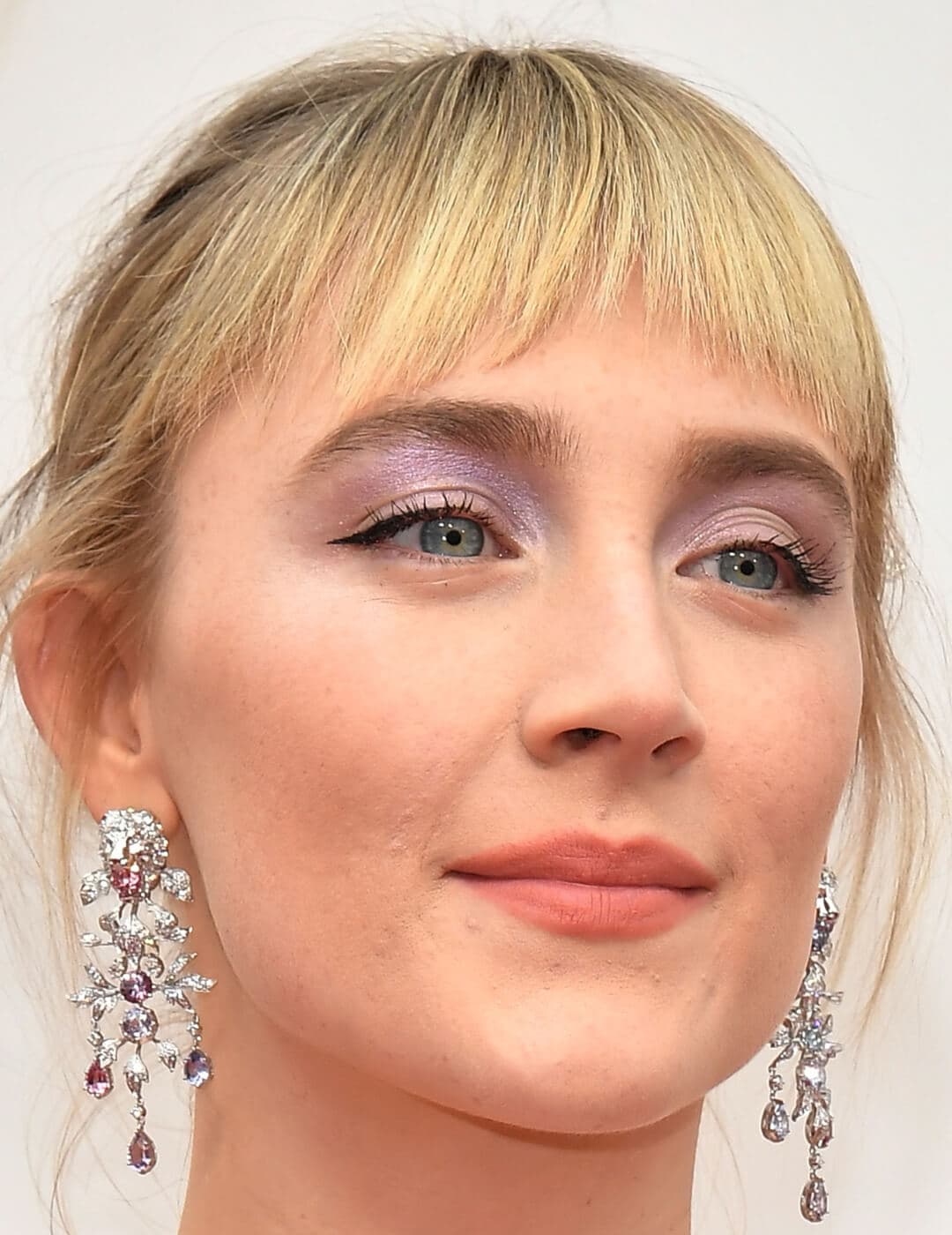 Saoirse Ronan rocking shimmery lavender eye makeup and silver dangling earrings on the red carpet