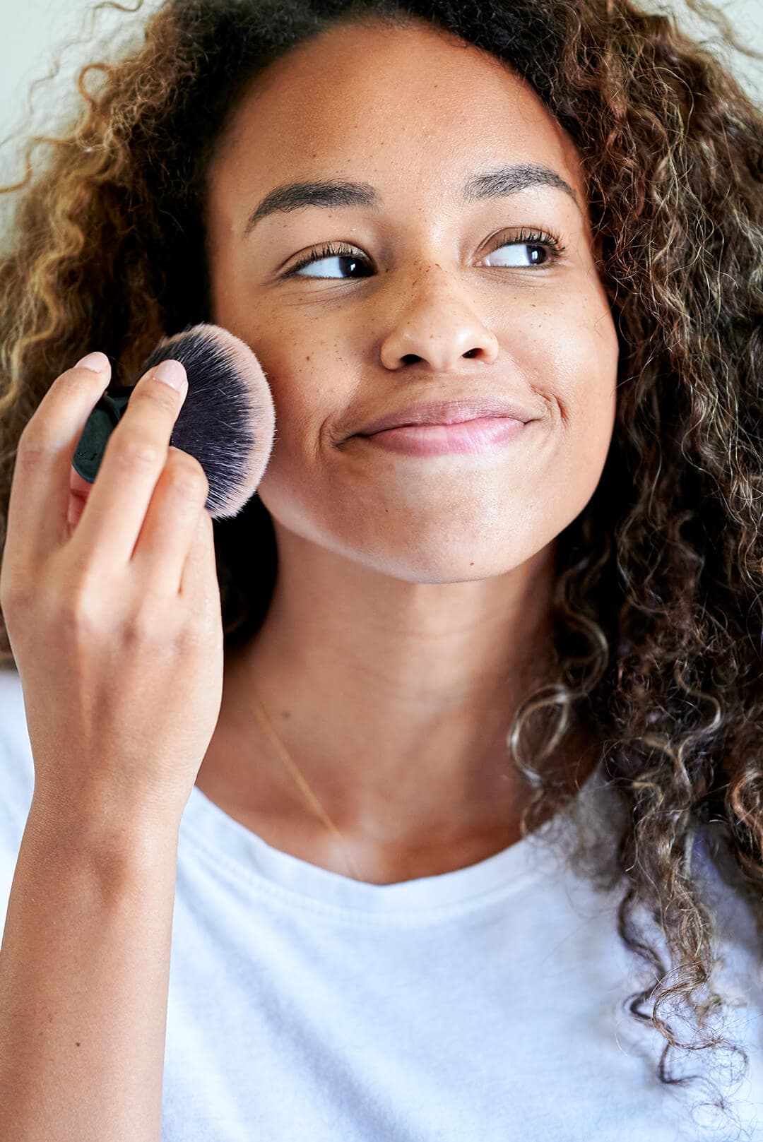 A photo of a woman applying face powder with a makeup brush against ...