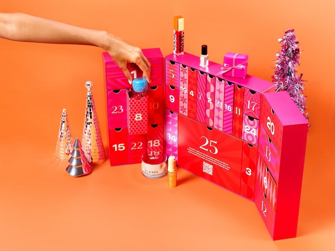 IPSY 2024 Beauty Advent Calendar open on an orange background with a IPSY 2024 Beauty Advent Calendar open on an orange background with a