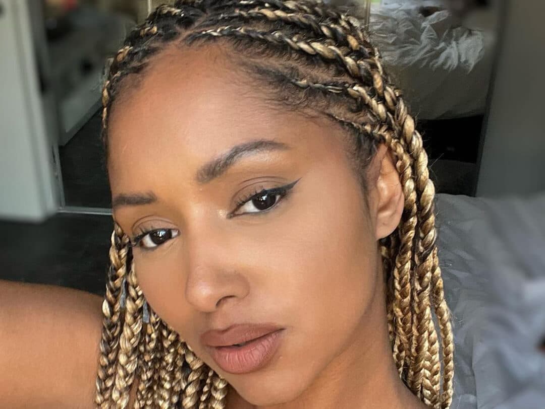 Not Less Fonly Braids A closeup photo of a model with a blonde knotless braids hairstyle