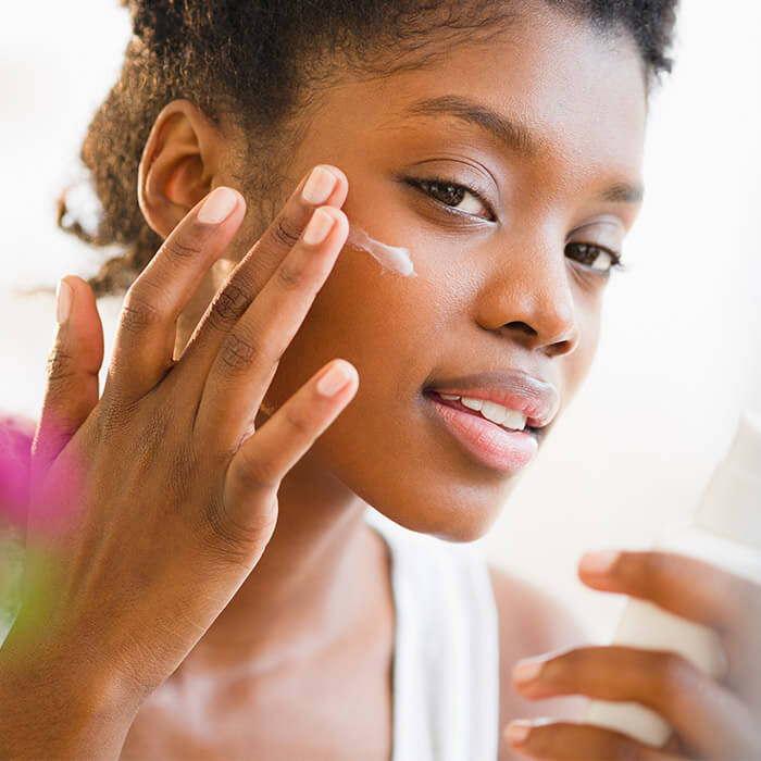 Close-up of a Black woman putting on face cream