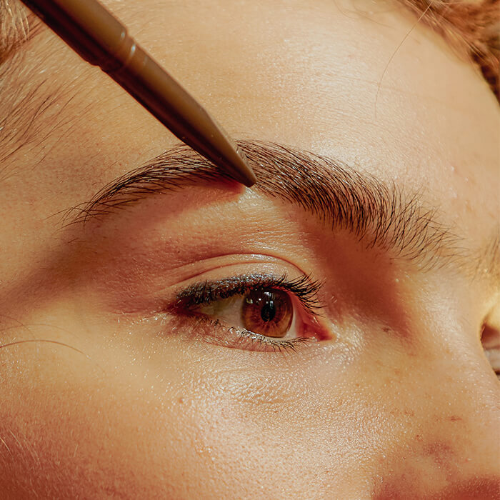 Close-up of a woman filling her brows with a brow pencil