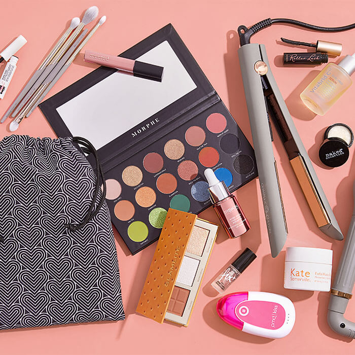 Makeup, skincare, and hair styling products and tools from various brands on peach background