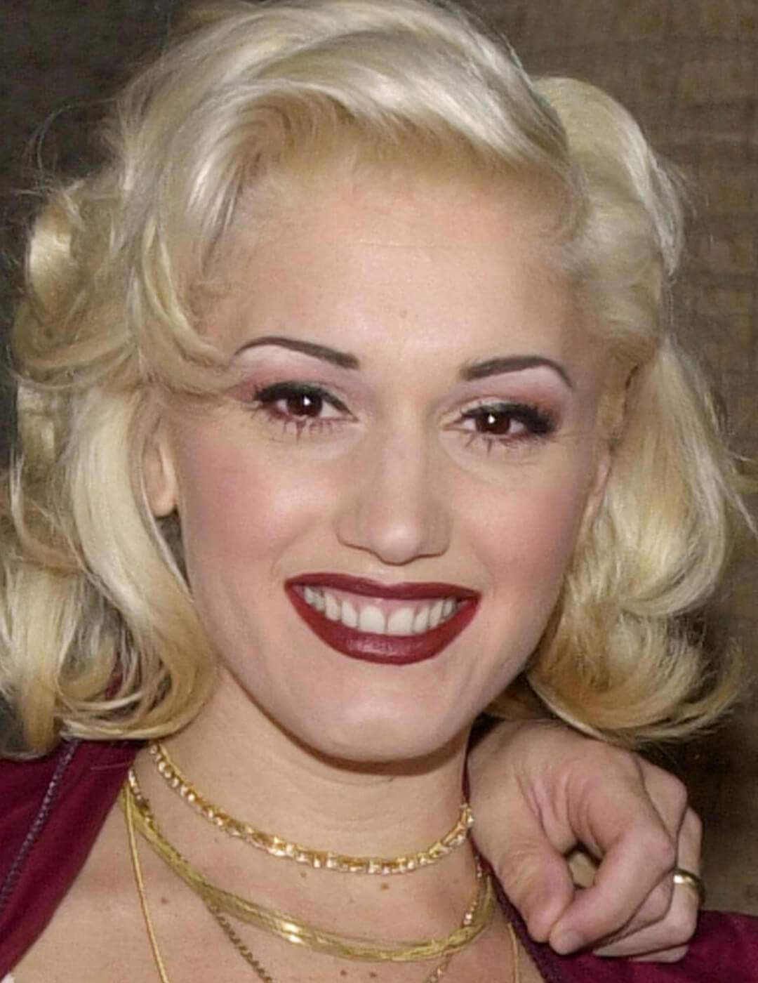 Younger Gwen Stefani rocking pencil thin eyebrows, shimmery pink eyeshadow, and dark red lips