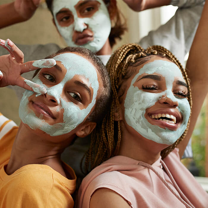 Smiling and posing young women with mud masks on their faces