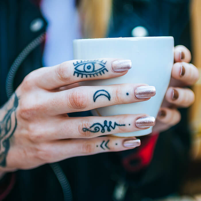 Close-up of tattooed woman's hand with coffee