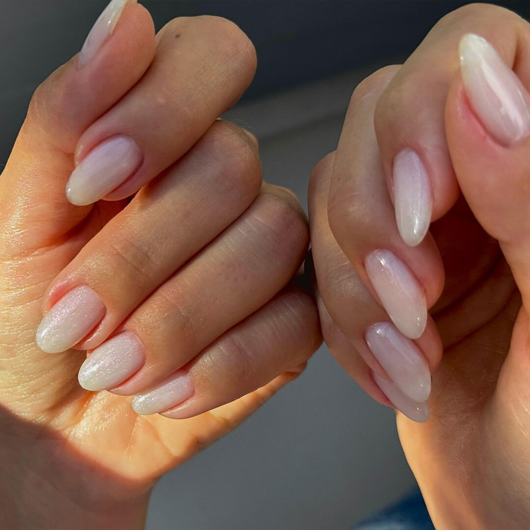 A detailed close-up of nails featuring a soft light pink and white color combination