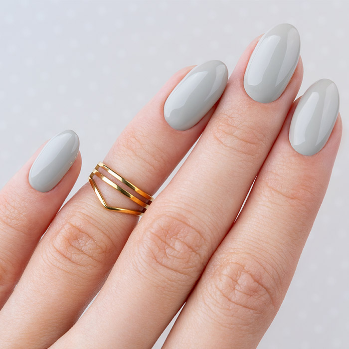 A photo of a woman's hand with a gray oval-shaped nails and a gold ring on it