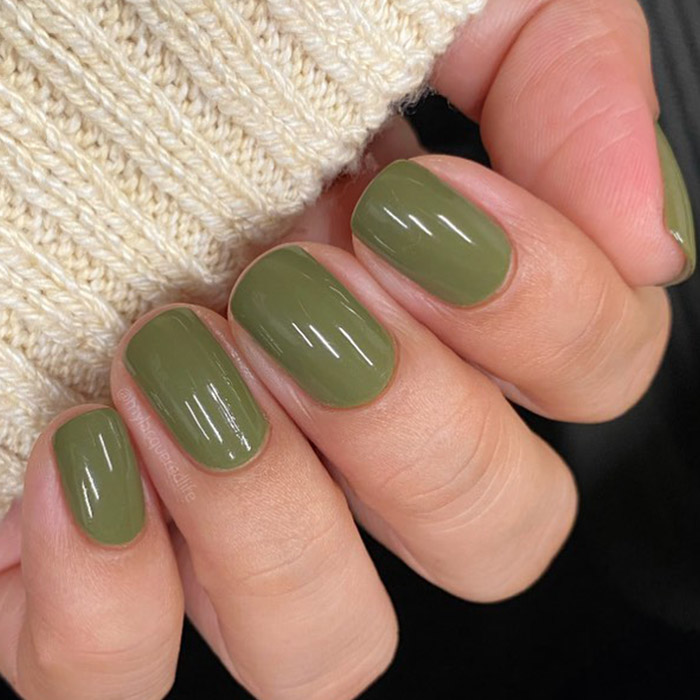 A closeup a model's hand with green nail polish