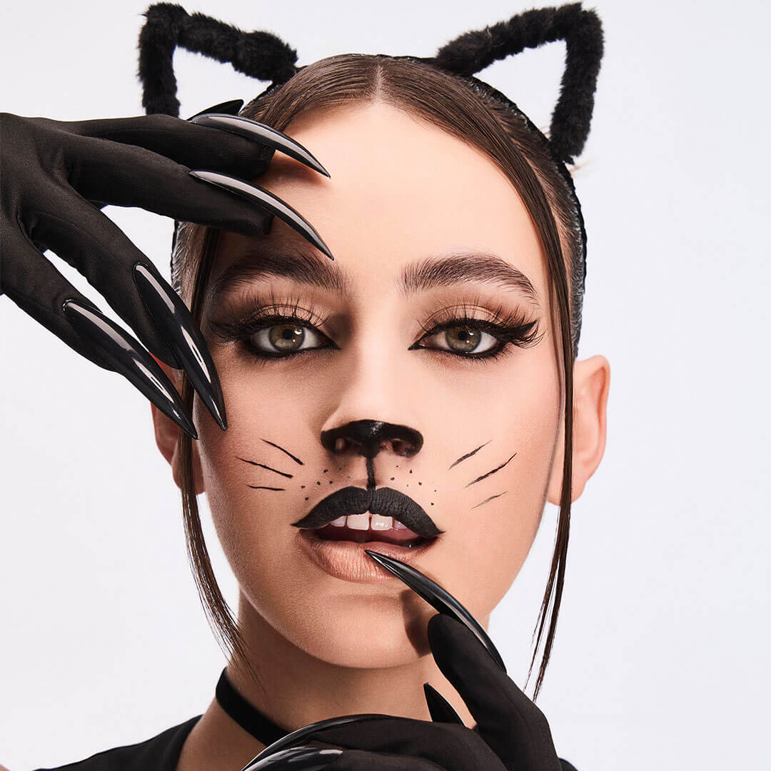 An image of a woman cosplaying as a cat woman wearing a black gloves with long black nails and a cat-ear like headband