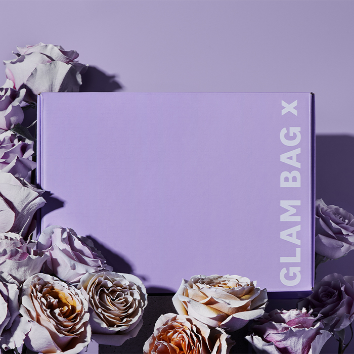 A photo of the Glam Bag X box with purple flowers on a purple background