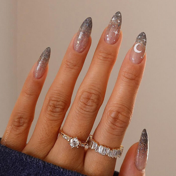 Close-up image of a woman's hand with glittery stars and moon nail art