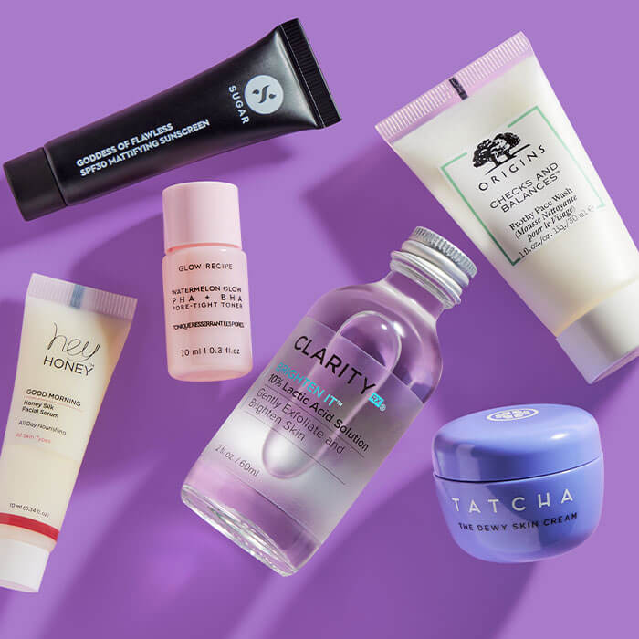 Skincare products from various brands scattered on purple background