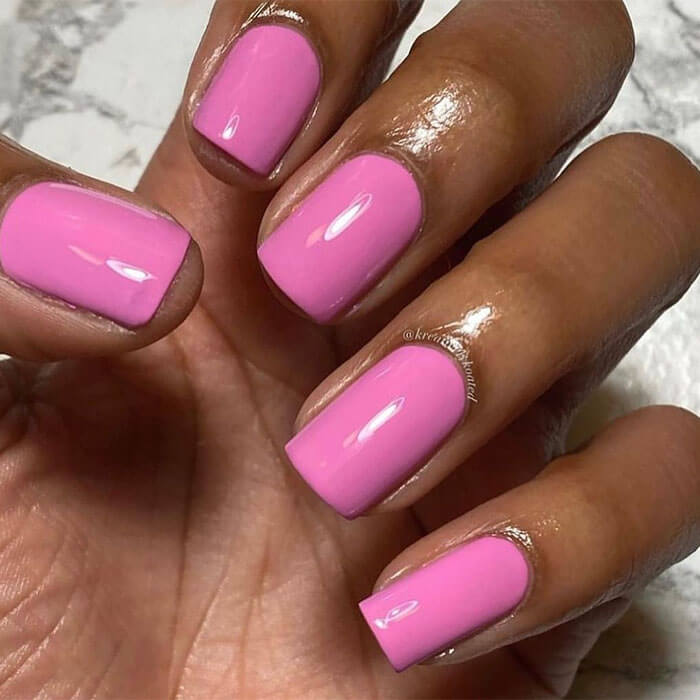 A closeup photo of hand with bright pink nail polish