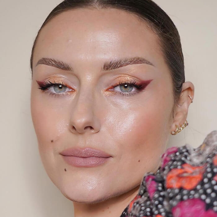 Close-up of a woman rocking a peachy glitter eye makeup look paired with nude lips