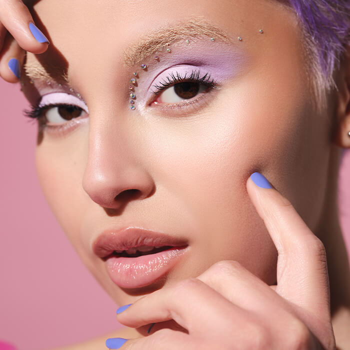 Close-up of a beautiful woman rocking a purple and rhinestone makeup look