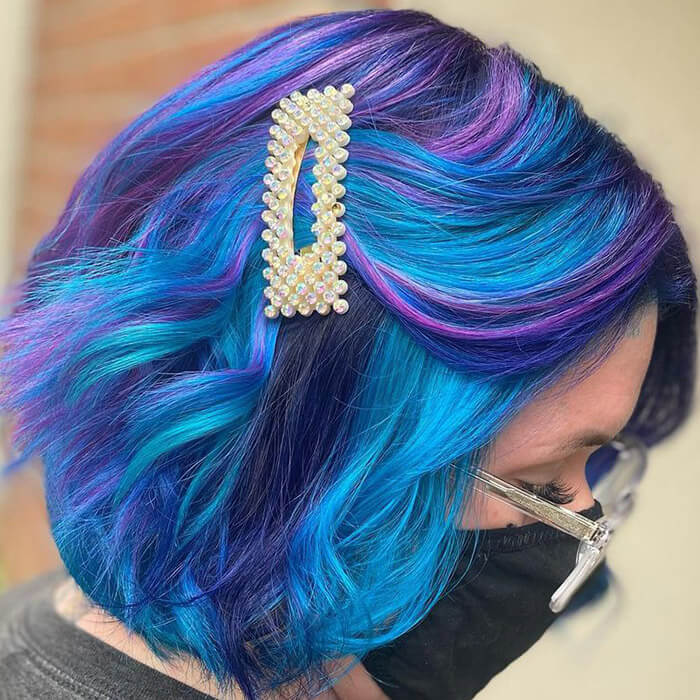 Close-up of a woman with face mask and eyeglasses rocking a galaxy-themed hair color