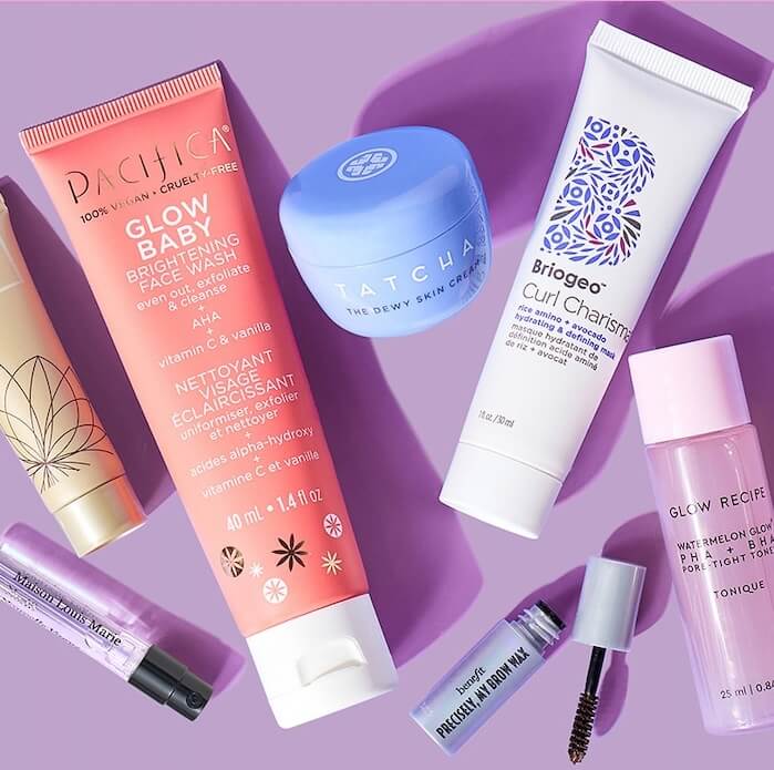 Close-up of travel-size IPSY Glam Bag and beauty products from various brands on pink background