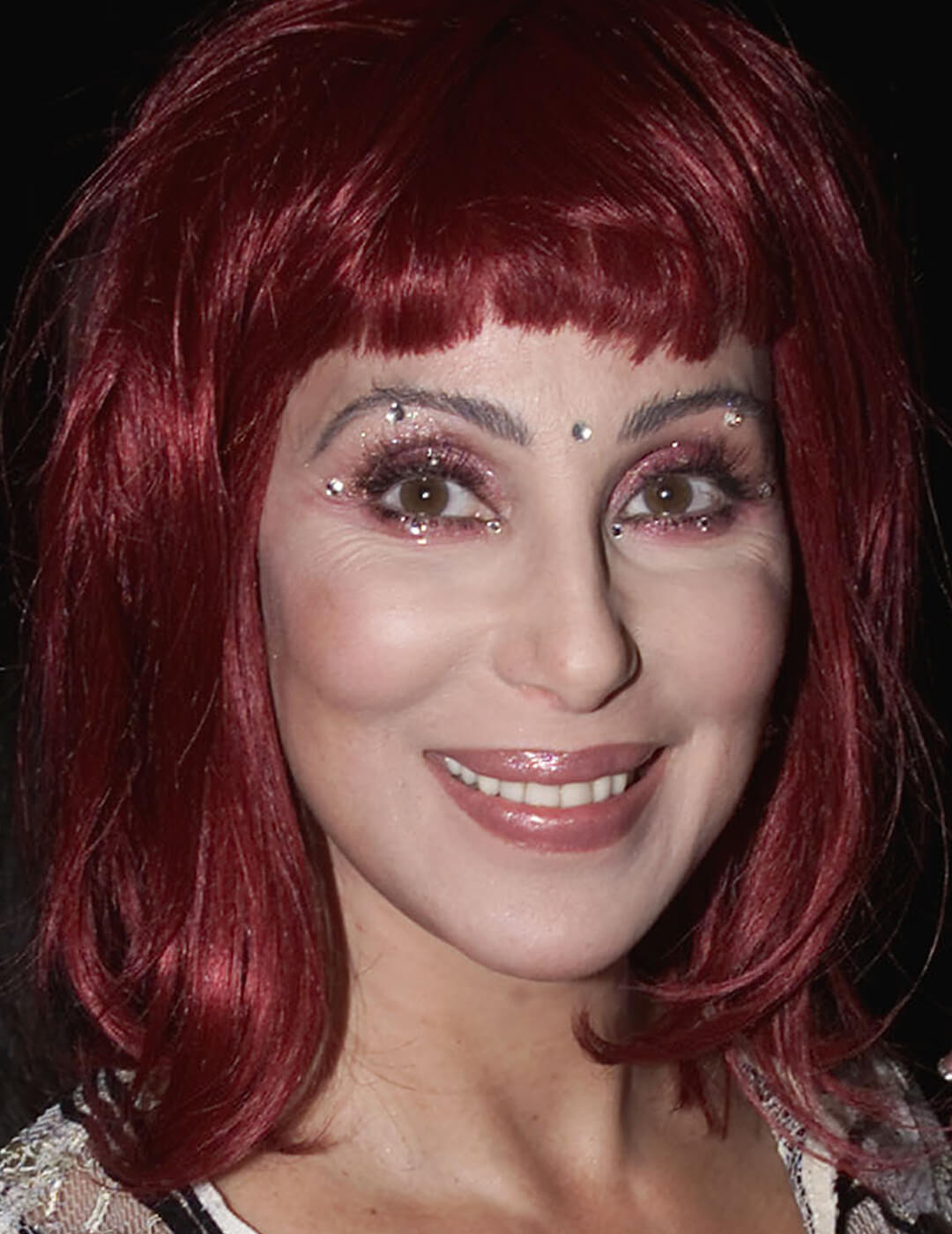 Younger Cher rocking burgundy hair, burgundy eyeshadow with gemstones, and nude lips