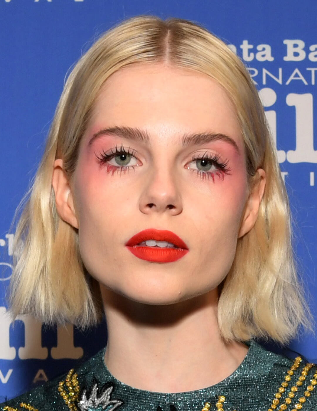 Lucy Boynton rocking a draped blush makeup look paired with bright coral lips