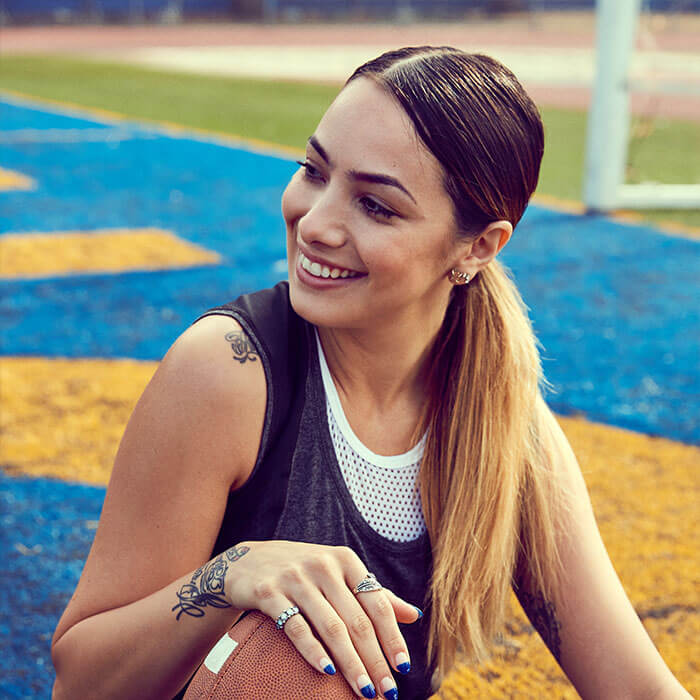 An image of a cheerful, active woman is seated, cradling a ball in her hands, radiating sporty energy