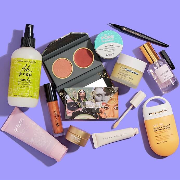 Skincare, makeup, and hair care products and tools from various brands scattered on purple background