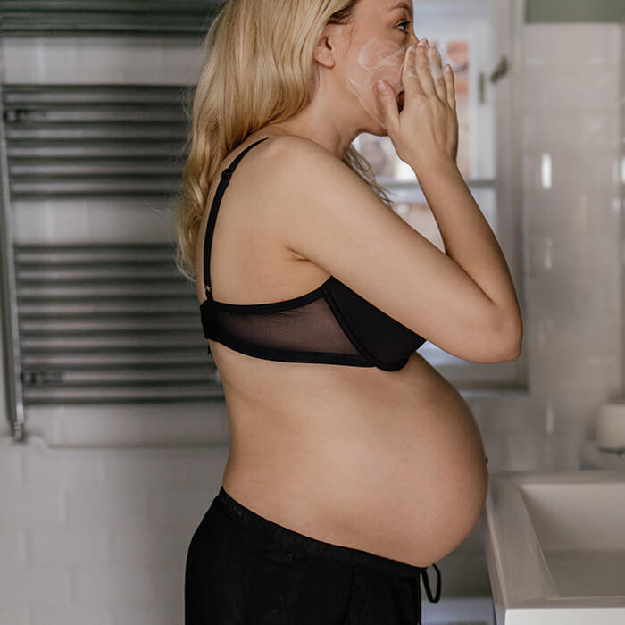 A photo of a pregnant woman in bathroom, doing her morning routine