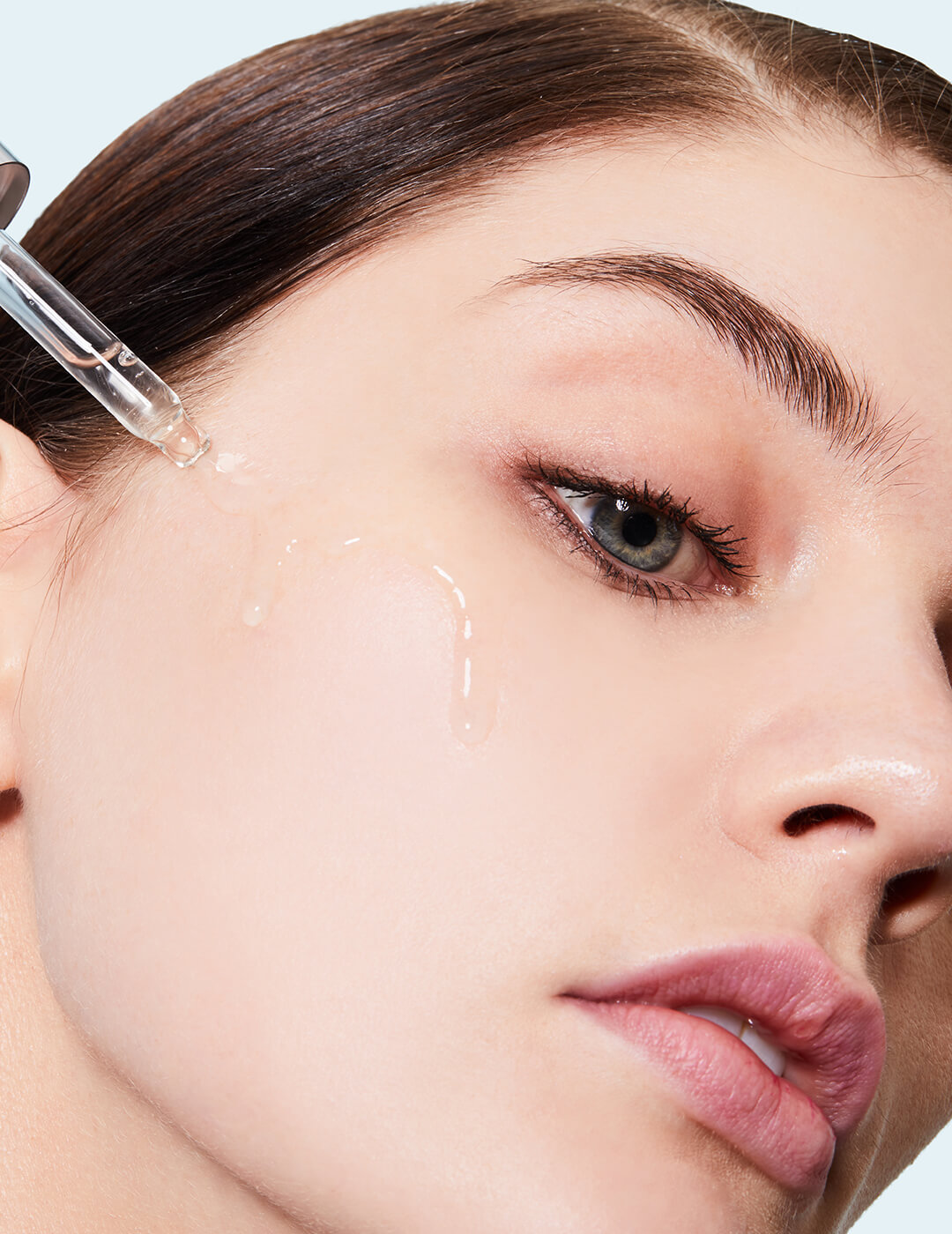 Close-up of a model applying serum on her cheeks