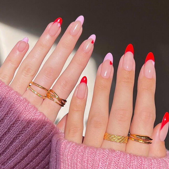 Close-up image of a woman's hands with light pink and red nail art