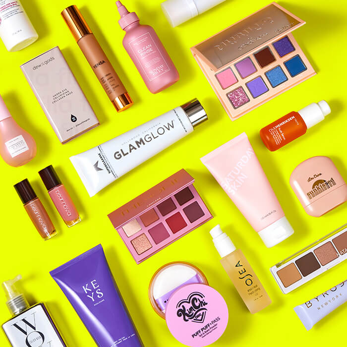 Flat lay image of different makeup and skincare products from various brands on neon yellow background