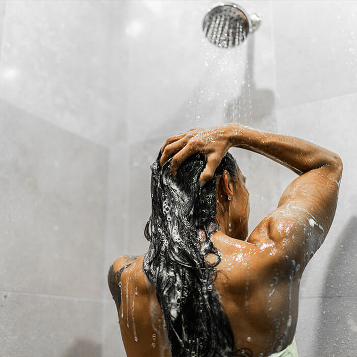 An image of a women  enjoying a bath inside the bathroom with bubbles adorning her hair