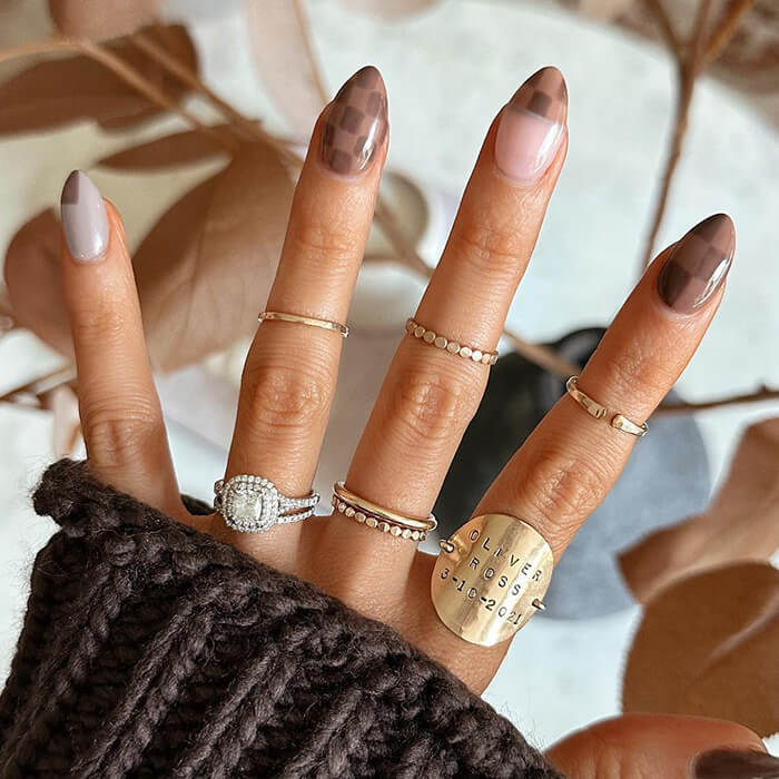 Brown and nude nail nail art on hand posed over fall leaves