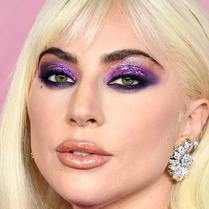 Lady Gaga rocking a glittery purple eyeshadow look paired with glossy lips on the red carpet
