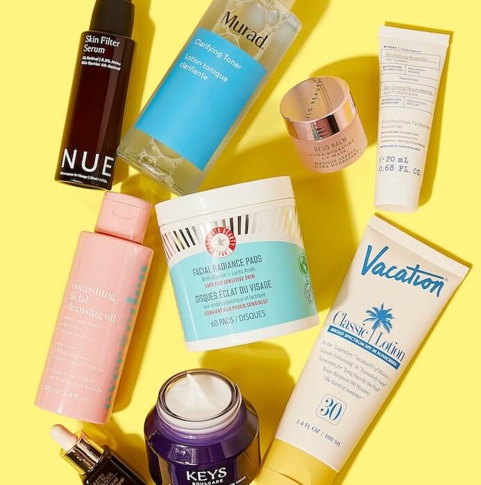 Flat lay image of skincare products from various brands on colorful yellow background