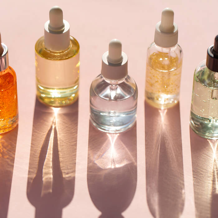 Bottles of oil with droppers on light pink background