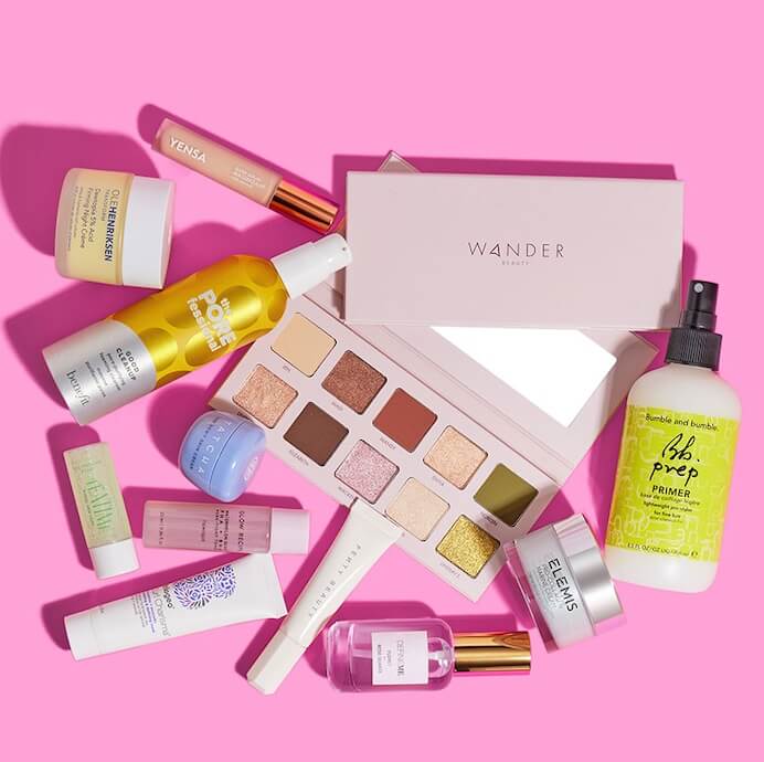 Skincare and makeup products from various brands scattered on pink background