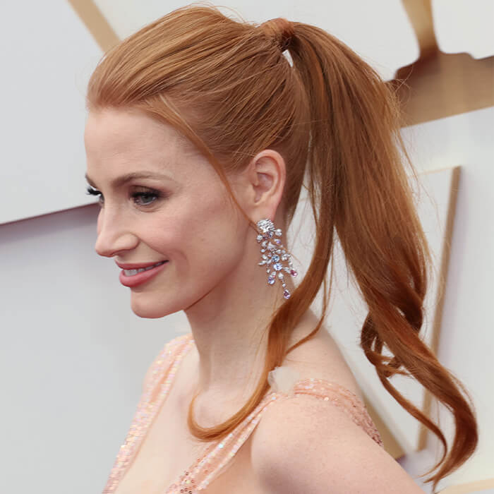 Jessica Chastain rocking a ponytail hairstyle, stone-studded dangling earrings and sequined pink dress at the red carpet